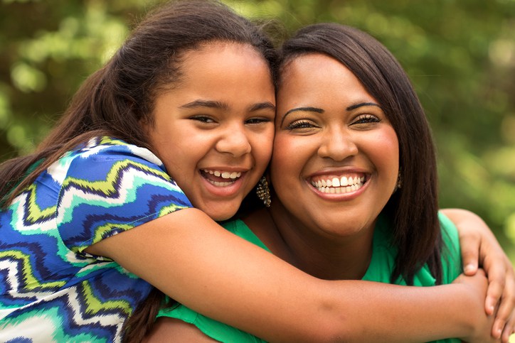 African American mother and daughter laughing and hugging each other.